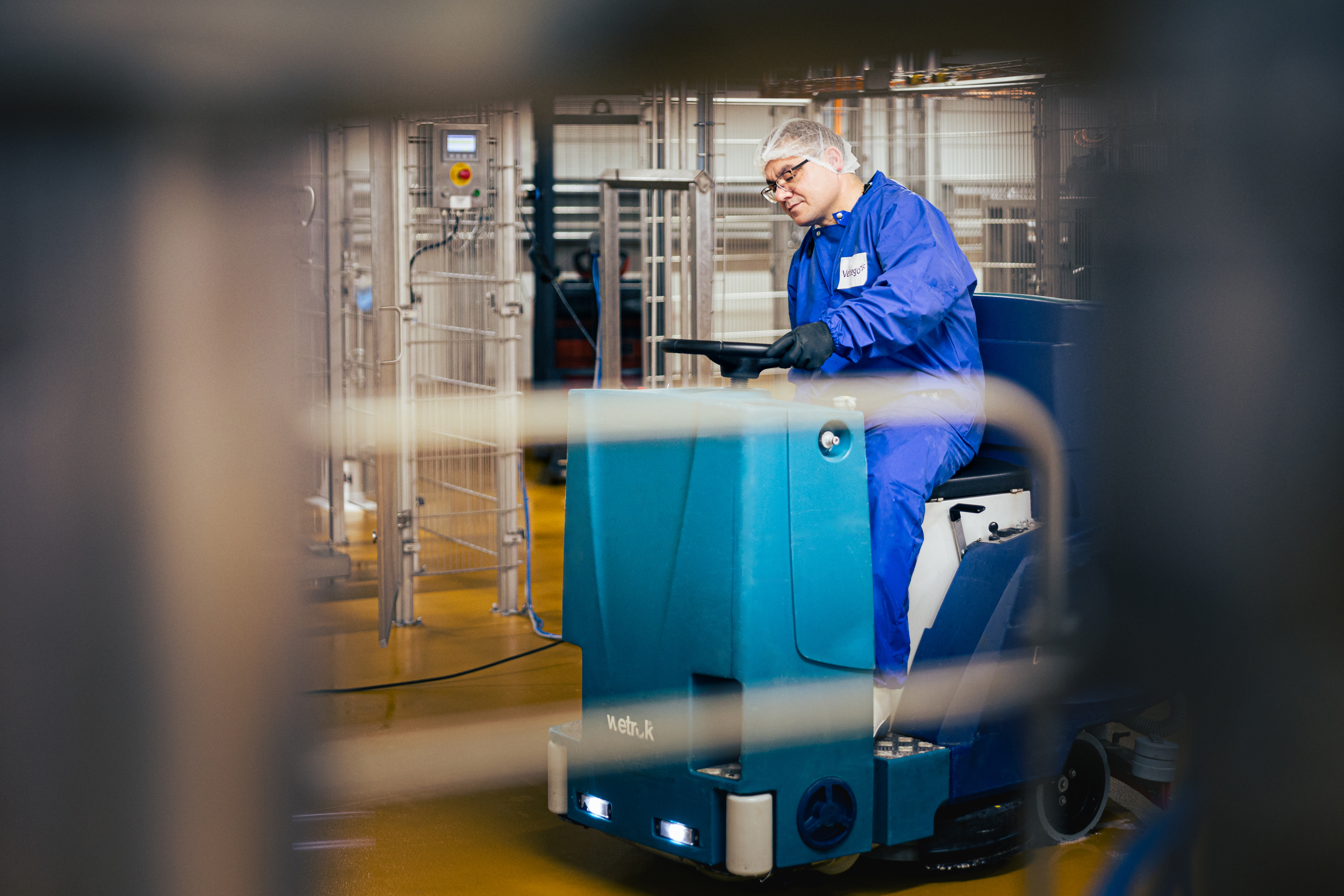 Een persoon reinigt de vloer van een faciliteit in de voedingsindustrie met behulp van een schoonmaakwagen