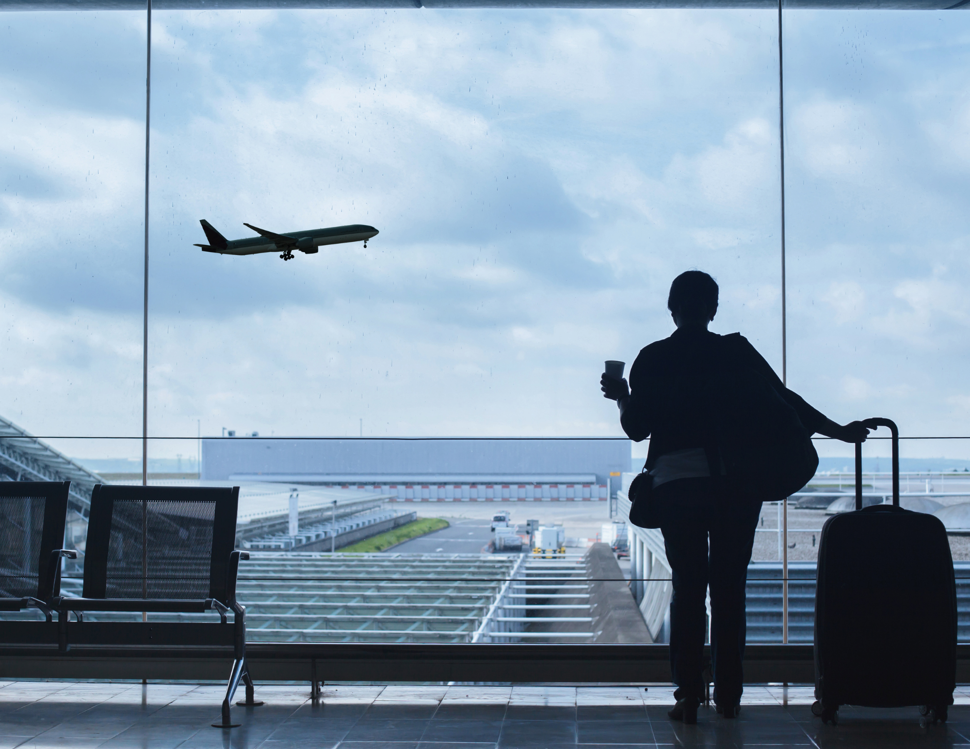 Een persoon kijkt uit het raam op een luchthaven